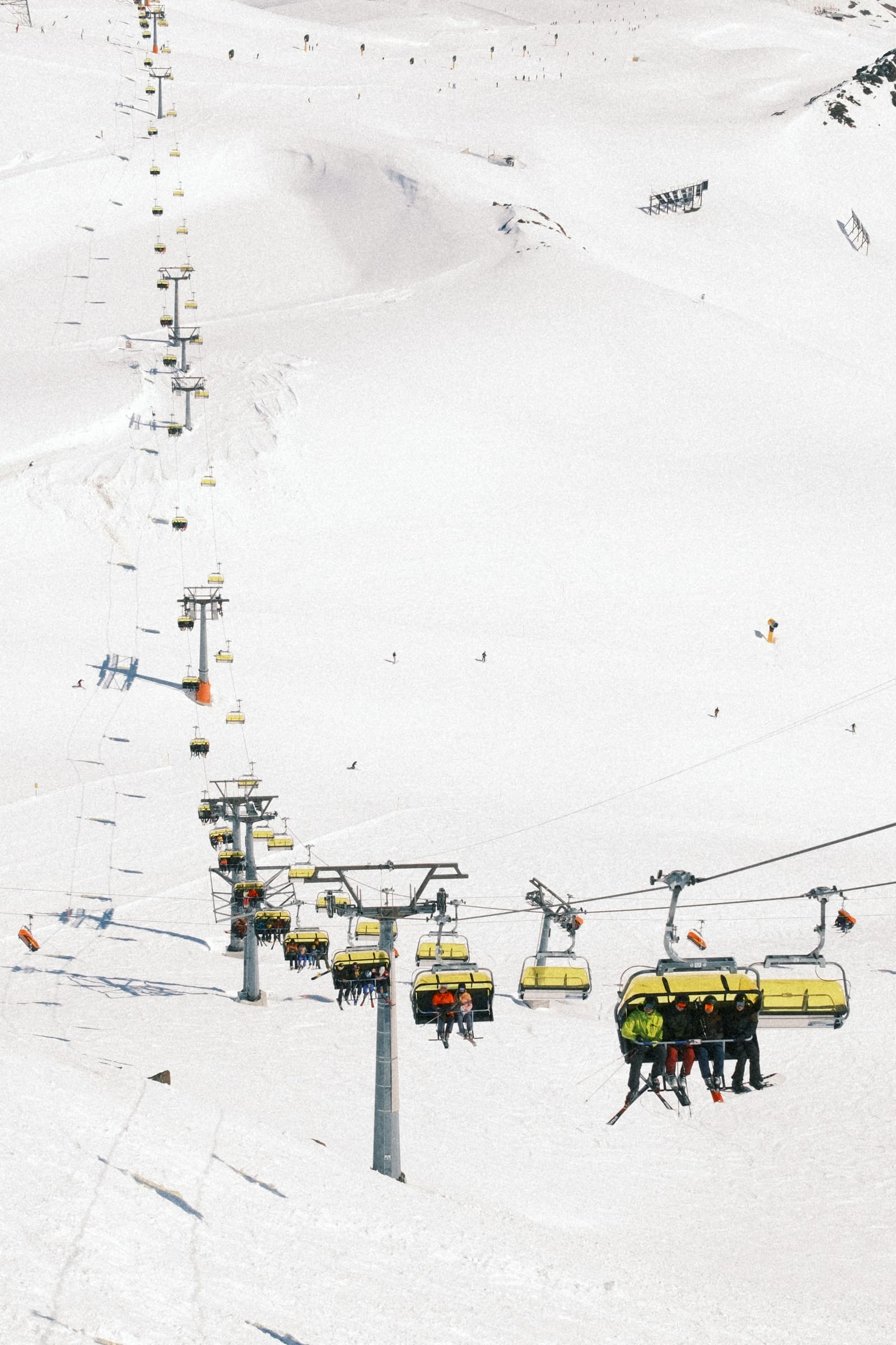 Sessellift mit gelben Hauben führt über ein weites, verschneites Skigebiet