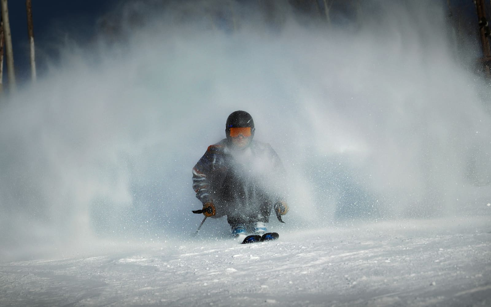 Skifahrer fährt aus einer Wolke aus aufgewirbeltem Schnee heraus