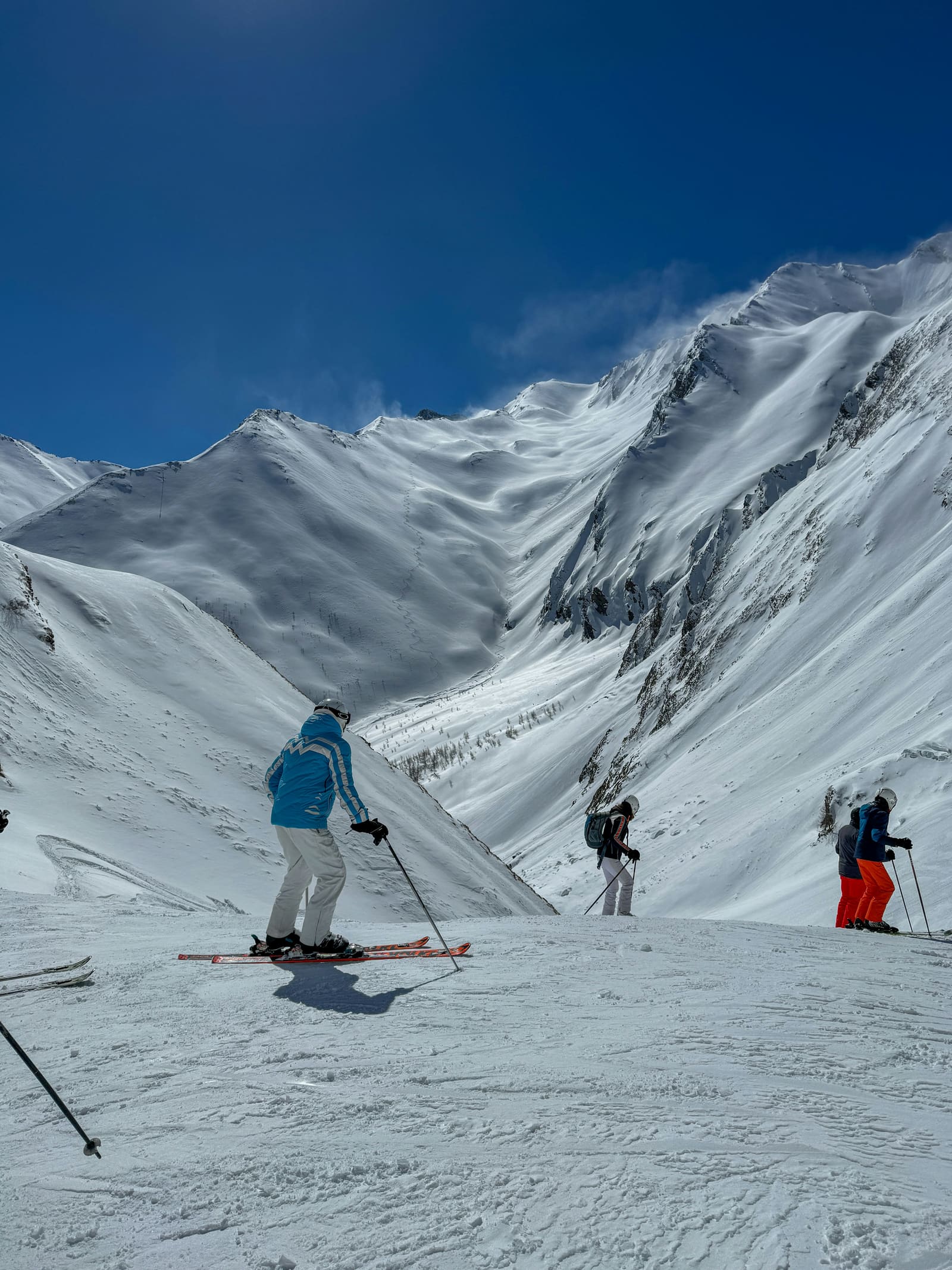 Skifahrer machen auf der Piste eine Pause vor weiten verschneiten Hängen