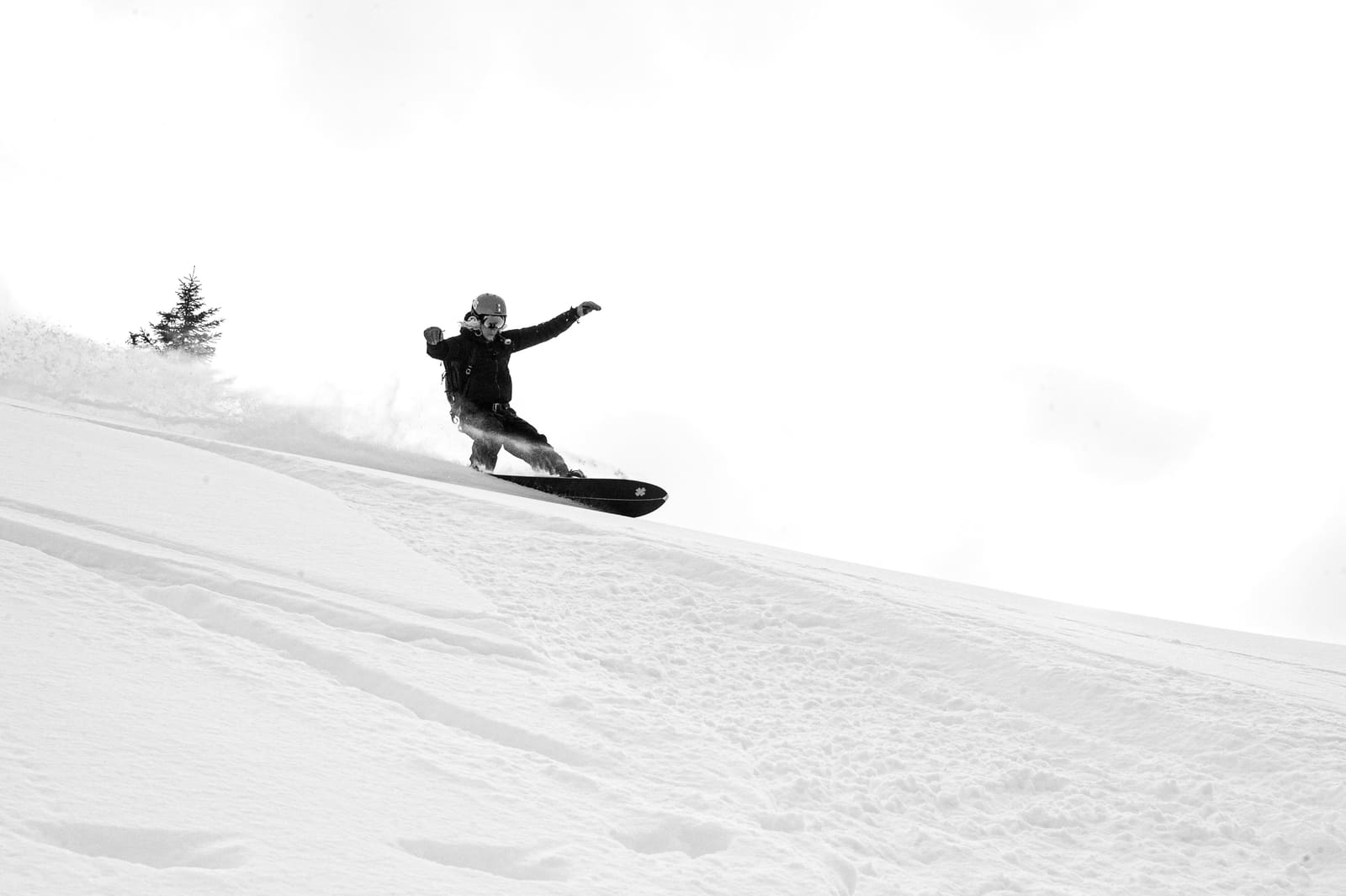 Snowboarder zieht einen Schwung durch Pulverschnee, Schwarzweissaufnahme